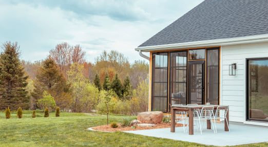 A rustic sunroom interior with beautiful view of the lake and a stone stacked fireplace 